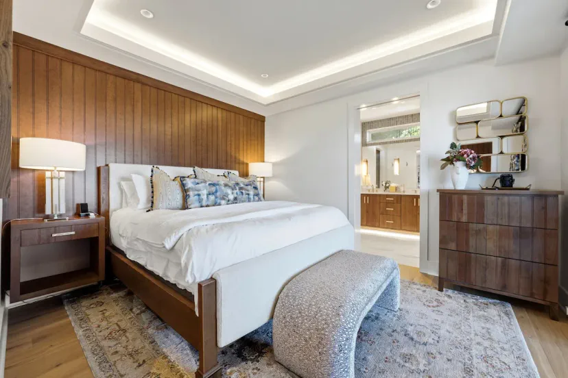 Suite principal con cama king y techo con iluminación LED, pared cabecera de panel de madera y banco tapizado — el dormitorio de lujo definitivo en Lake Burton, Tiger, Georgia.