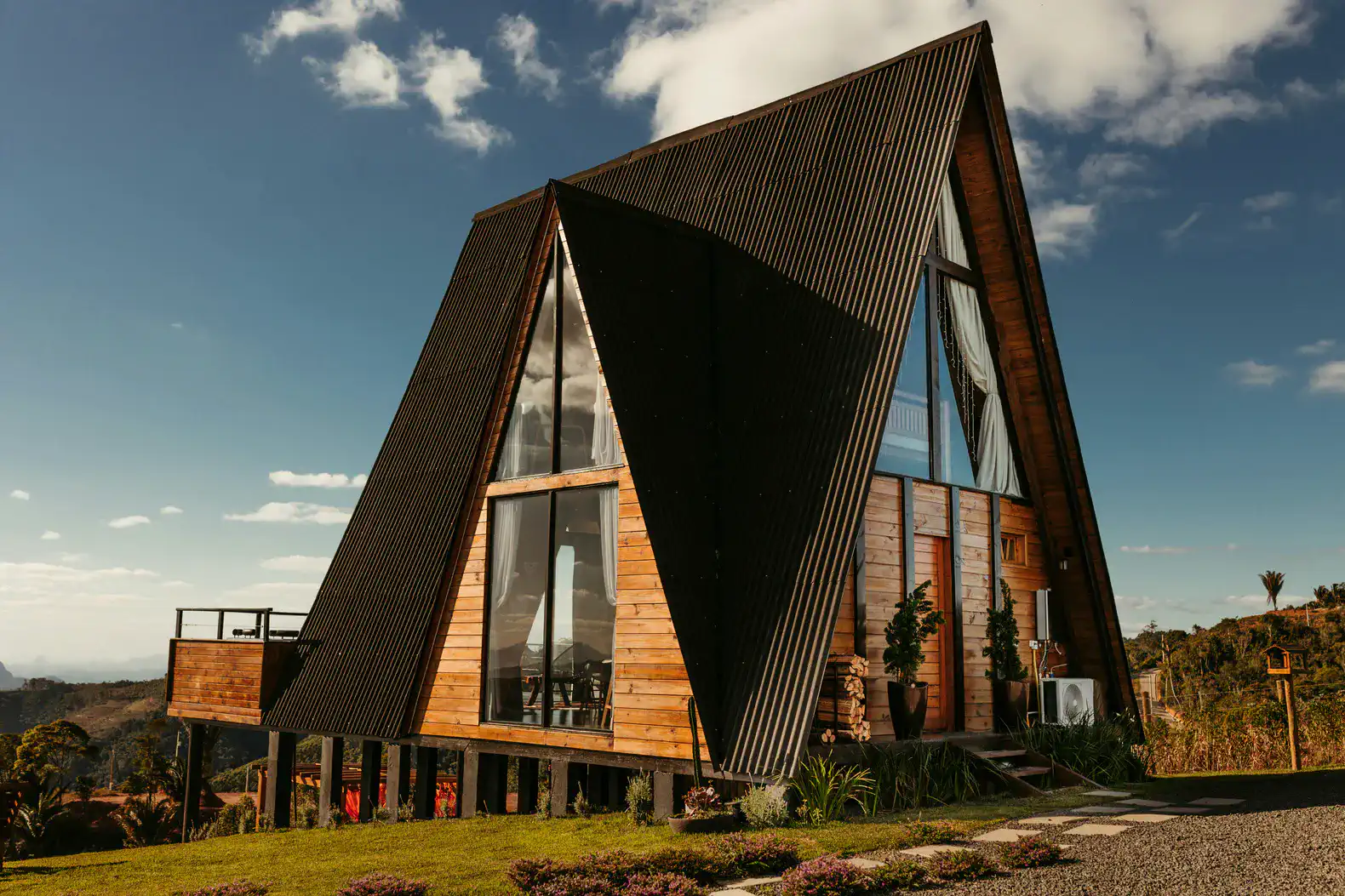 Stylish A-frame cabin with wooden exterior and large windows set against a blue sky