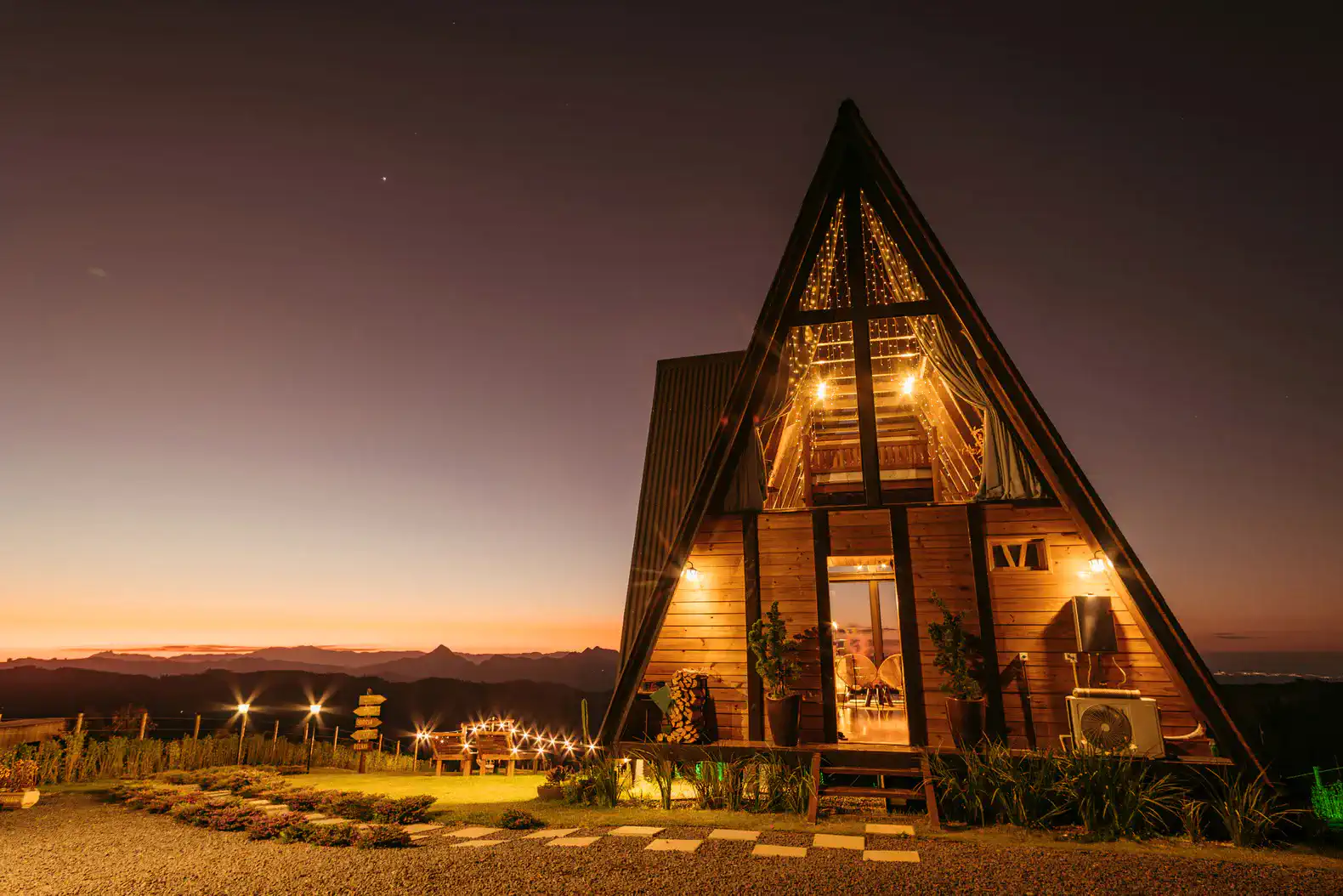 A stunning A-frame cabin illuminated at dusk with mountain views