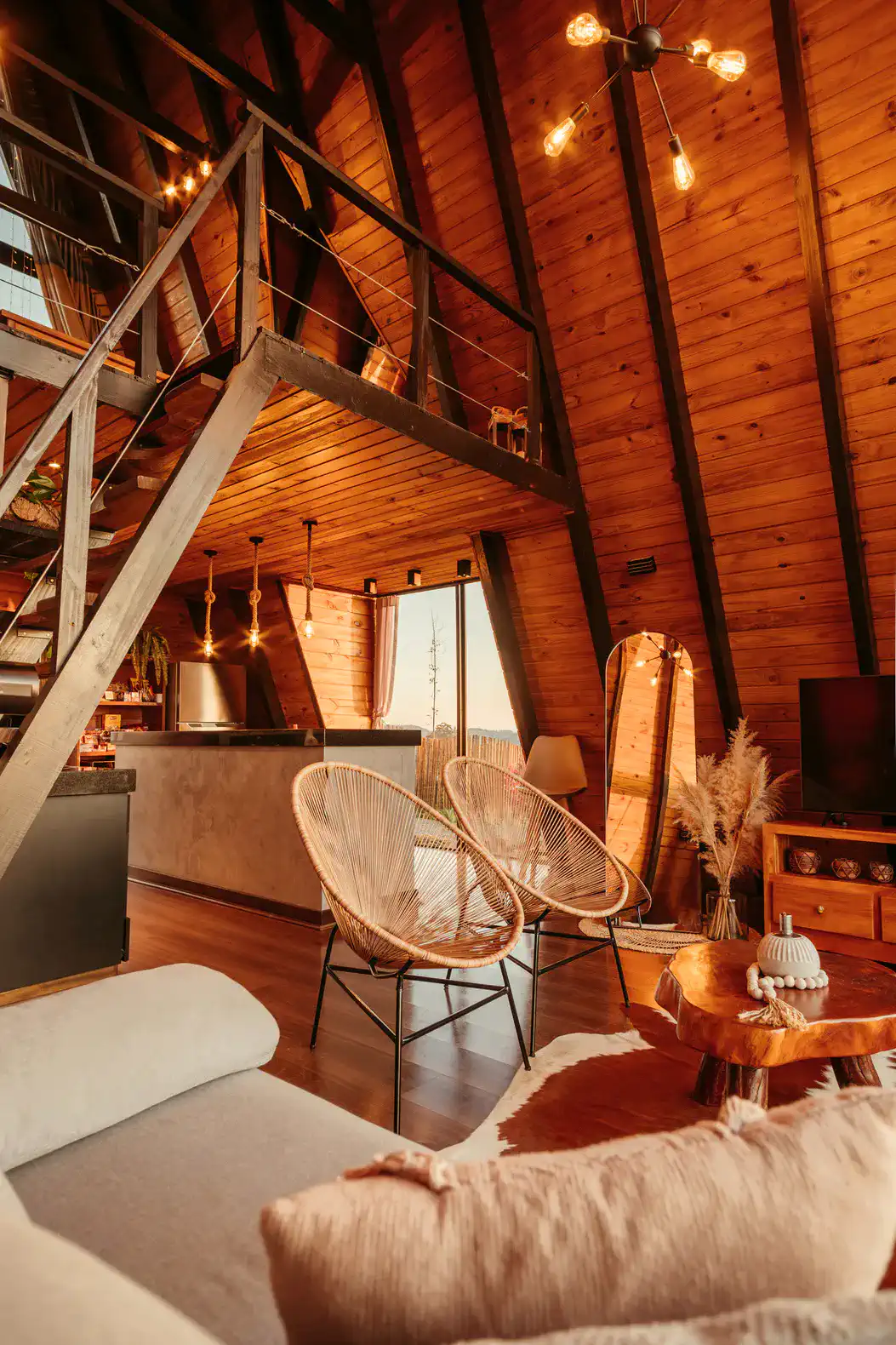 Cozy living area with wooden beams, stylish chairs, and a view of the kitchen