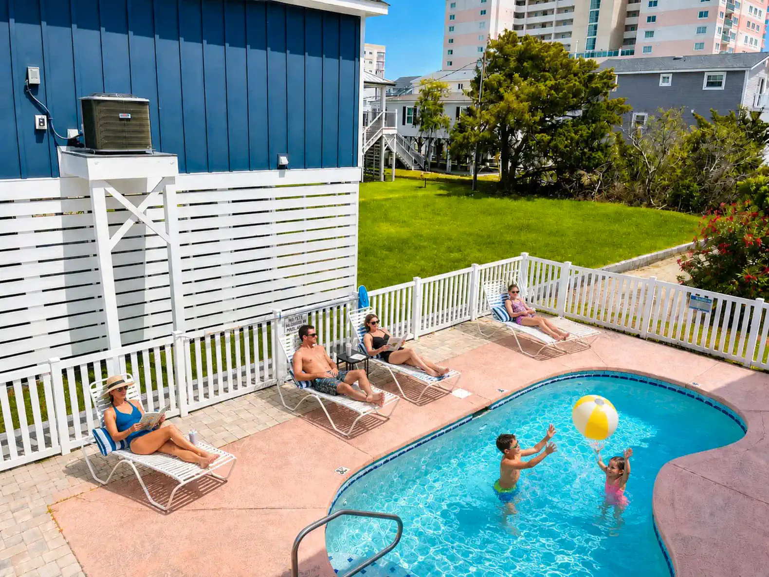 Guests enjoying the pool area with sun loungers and a beach ball