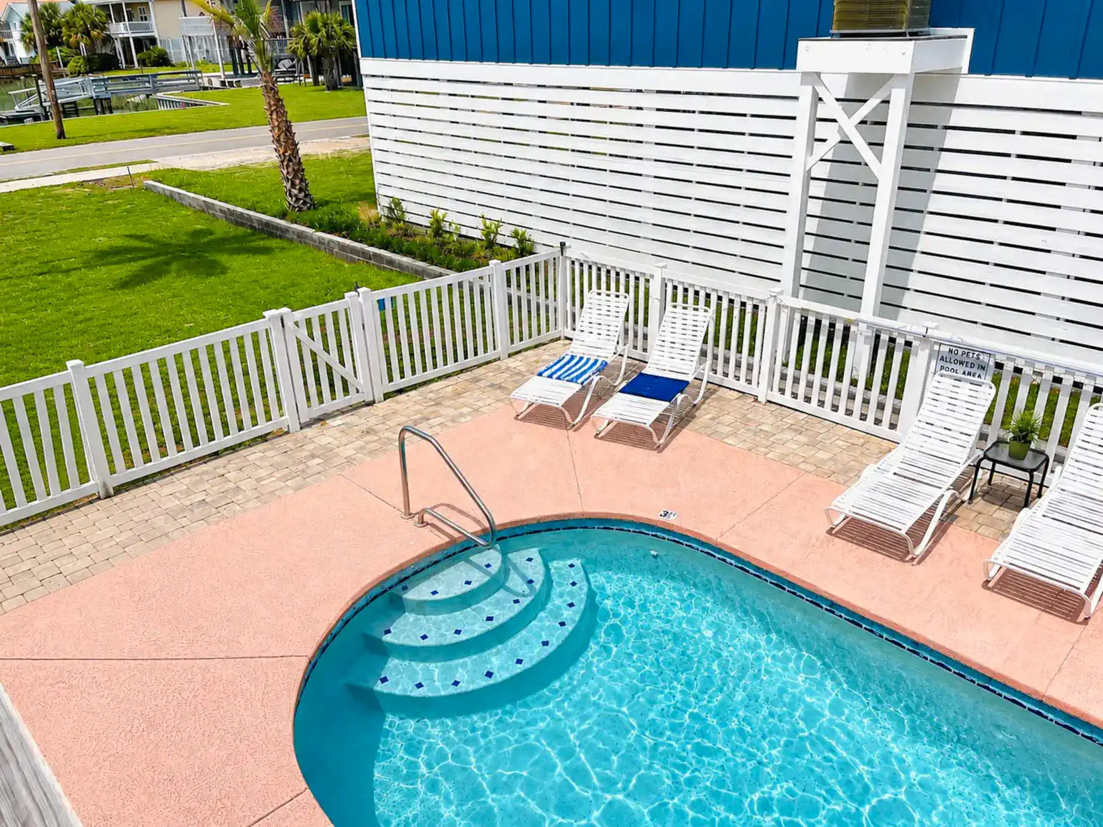 Private pool area with lounge chairs and a fenced yard