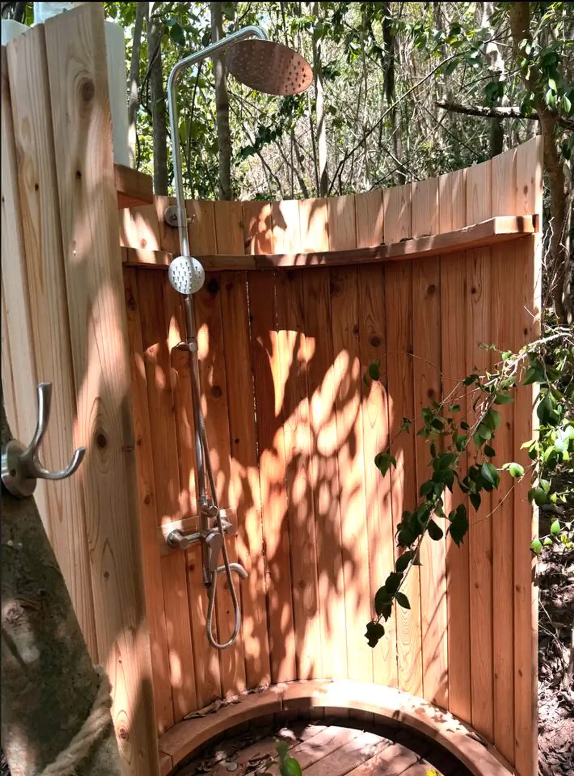 Outdoor shower surrounded by wooden fencing and greenery