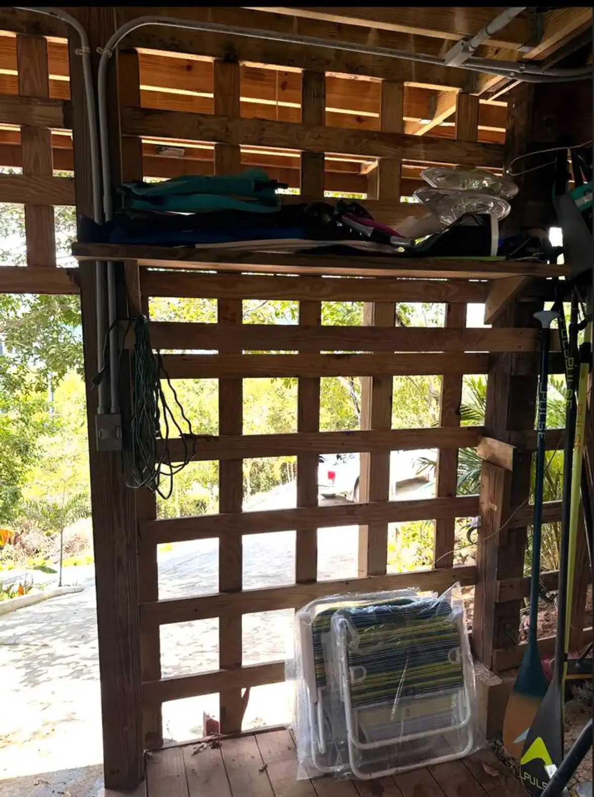 Wooden lattice wall with storage for outdoor gear and chairs