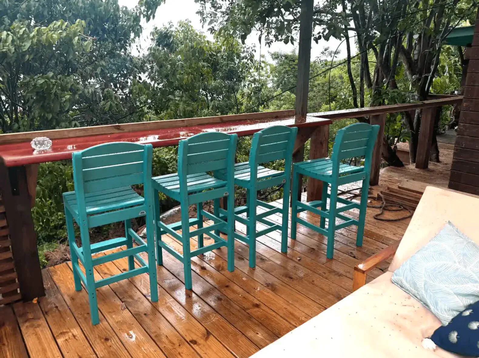Outdoor bar seating with turquoise stools overlooking lush greenery