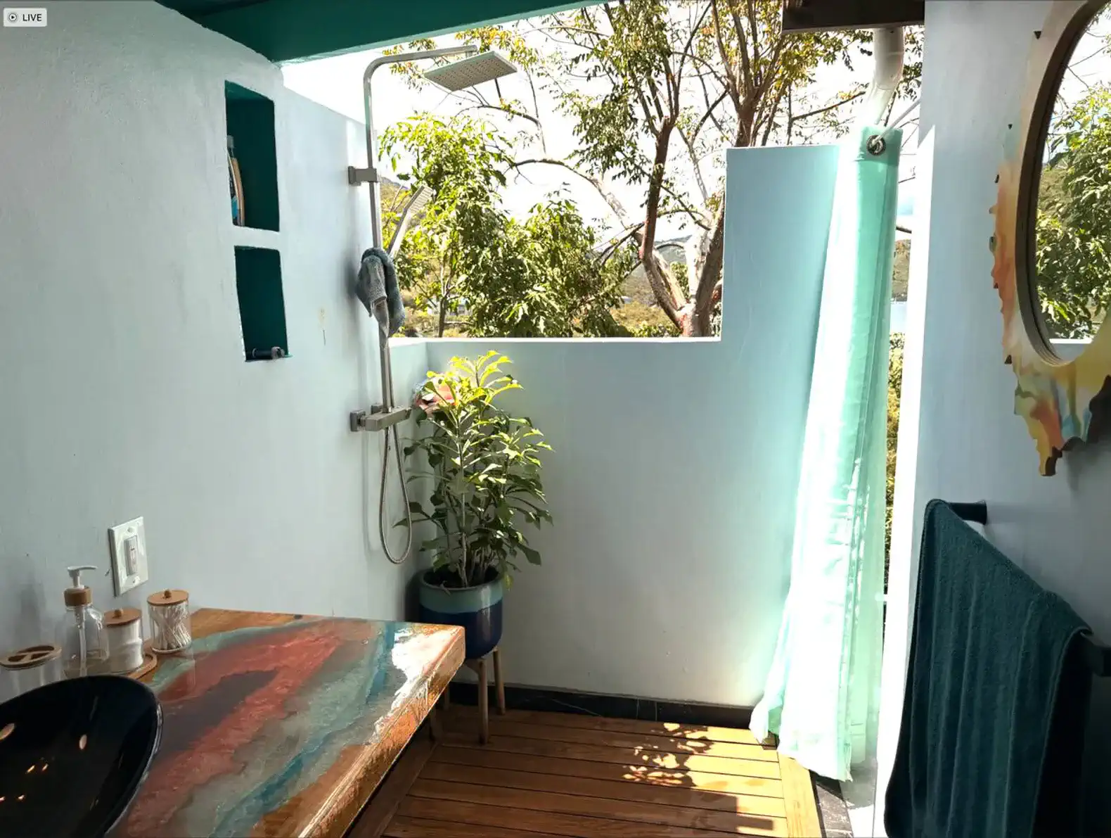 Outdoor shower area with wooden deck and greenery
