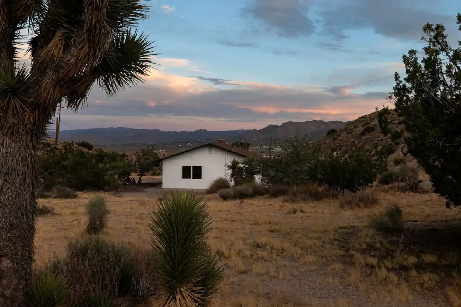 Scenic view of a white cabin surrounded by desert landscape and mountains
