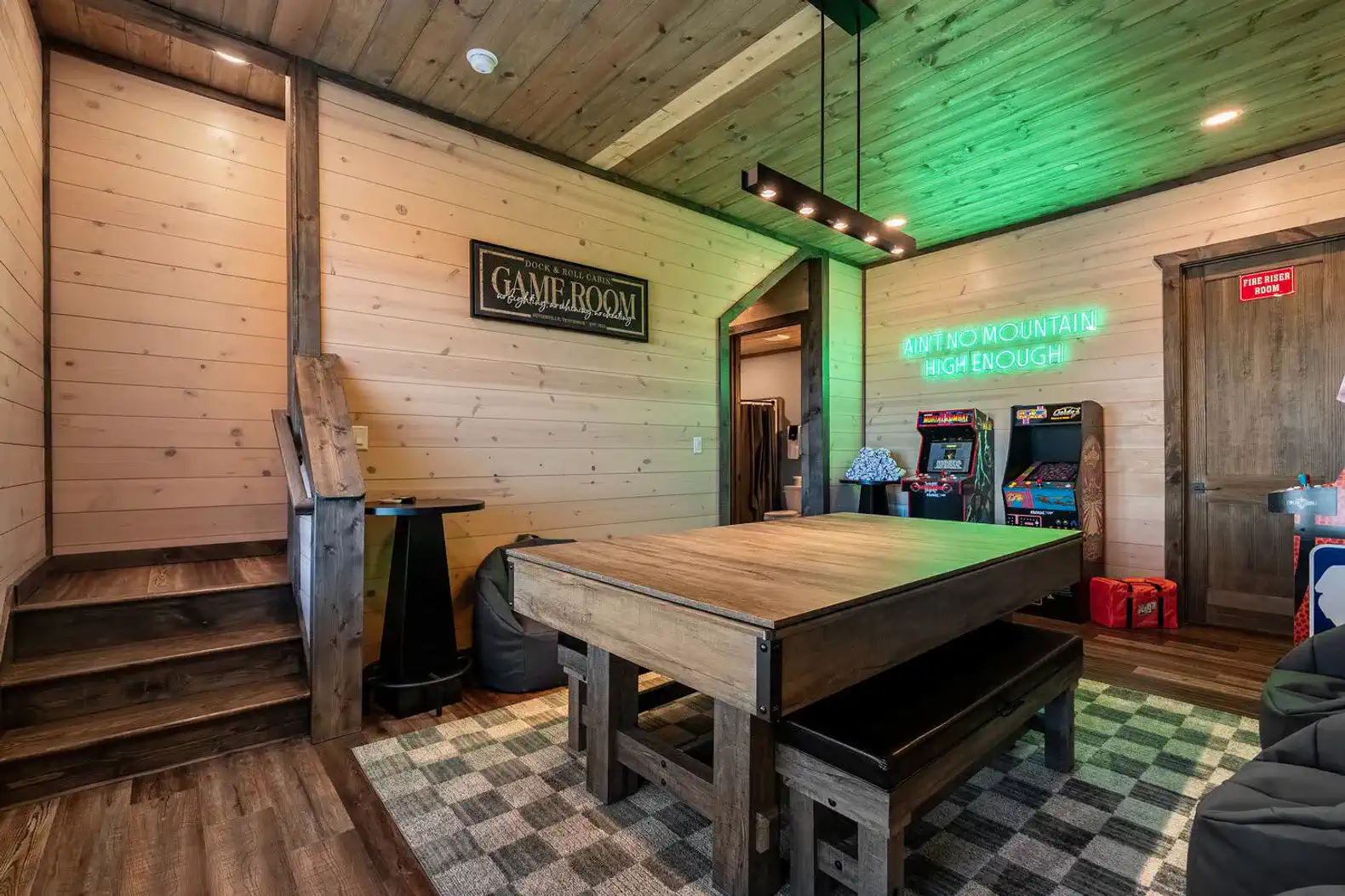 Spacious game room featuring a large table, arcade games, and wooden decor