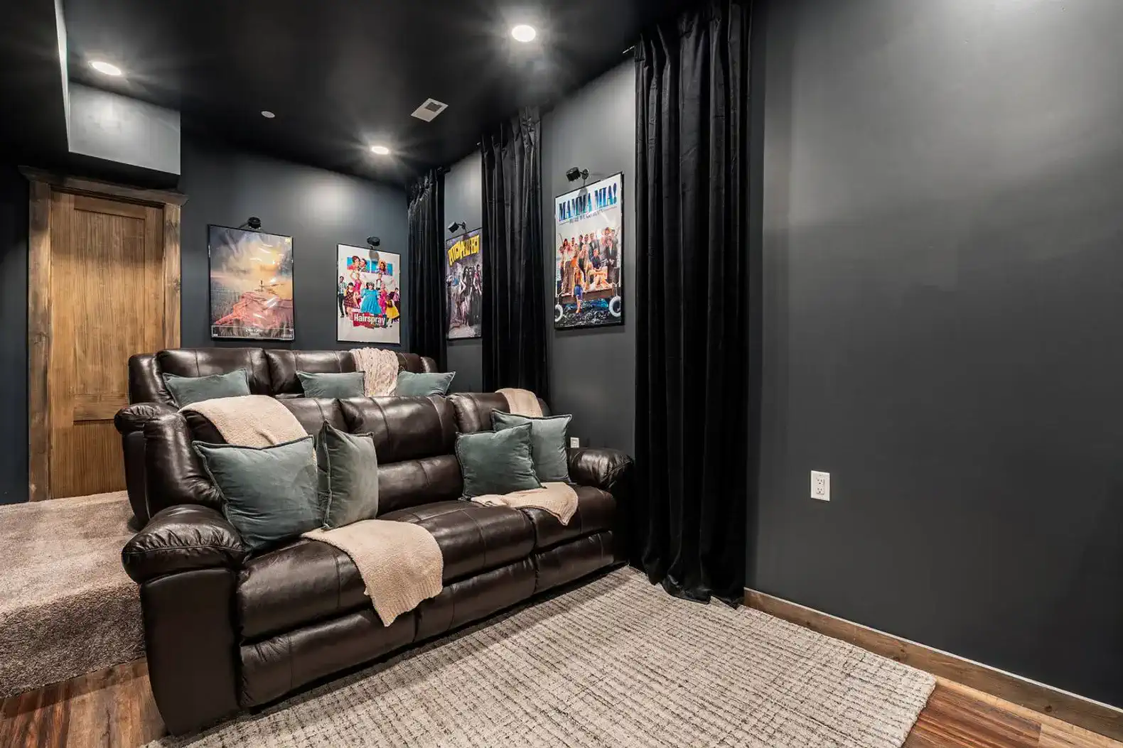 Cozy movie room with dark walls, plush seating, and movie posters