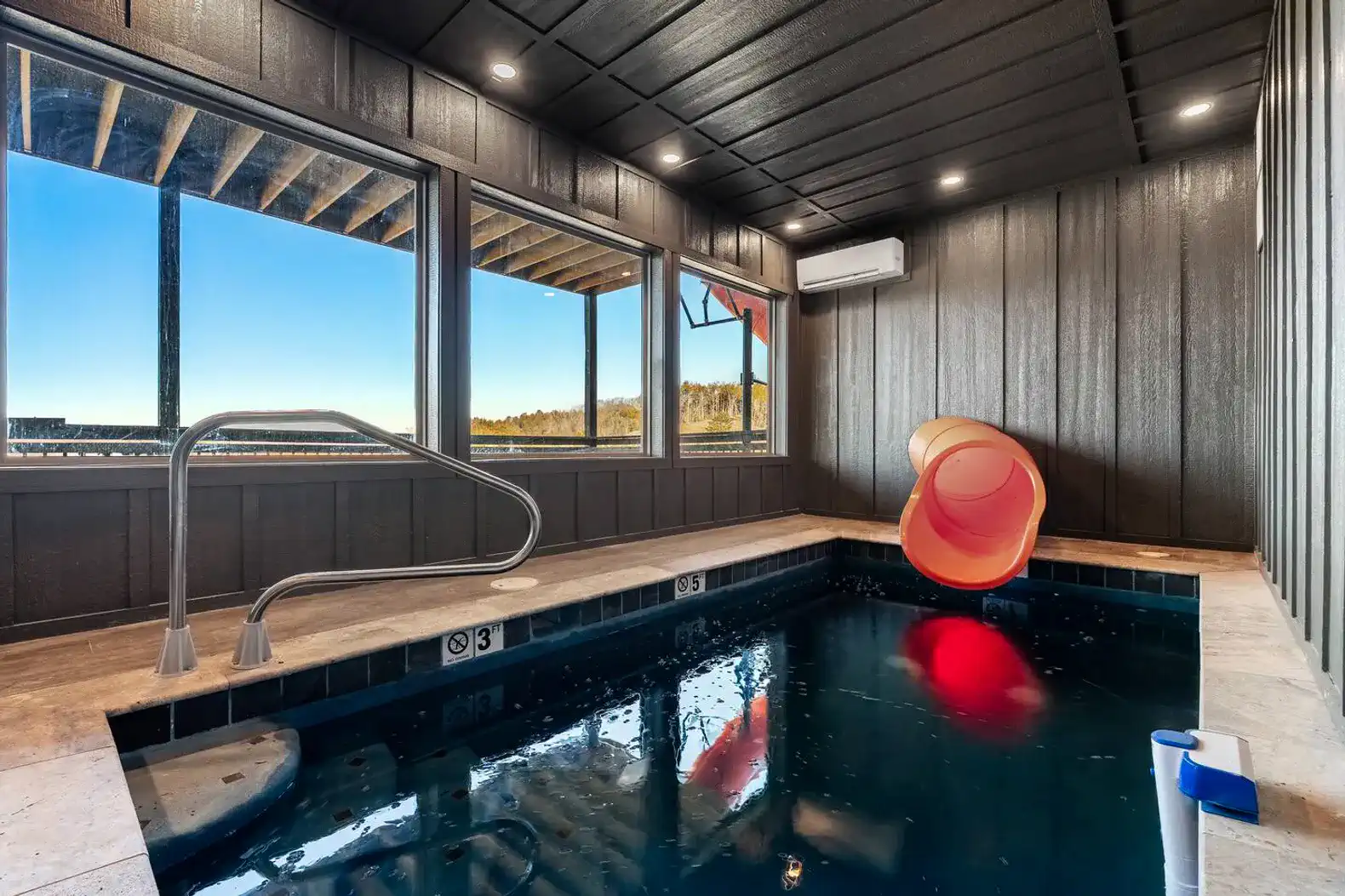 Indoor pool with a water slide and large windows offering scenic views