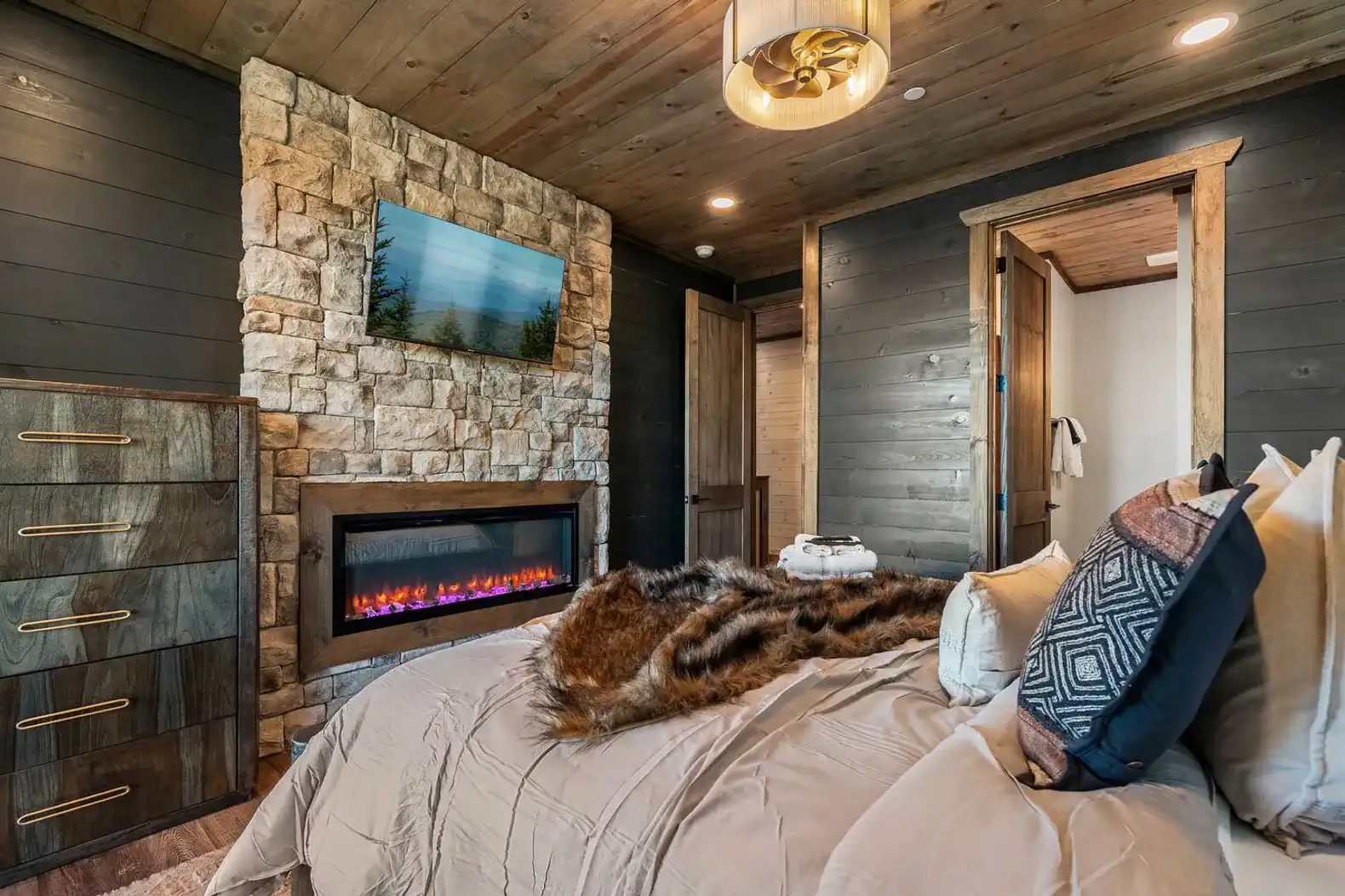 Cozy master bedroom with stone fireplace and modern decor