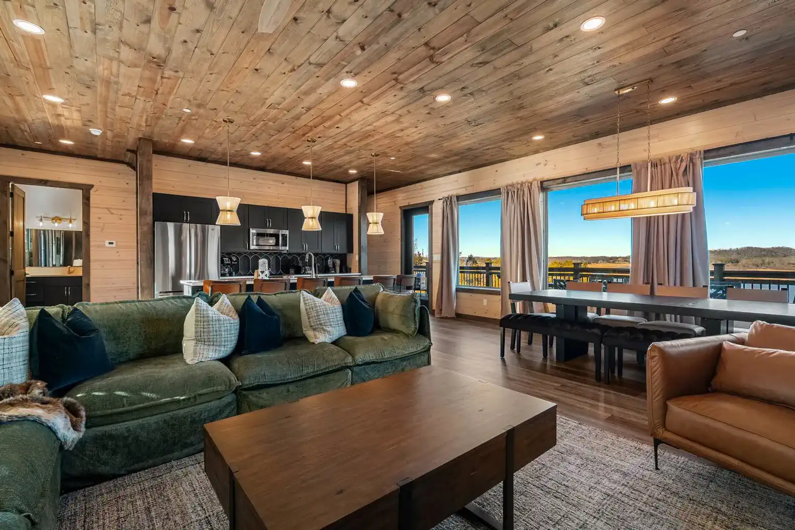 Spacious living area with wooden ceiling, large windows, and modern kitchen