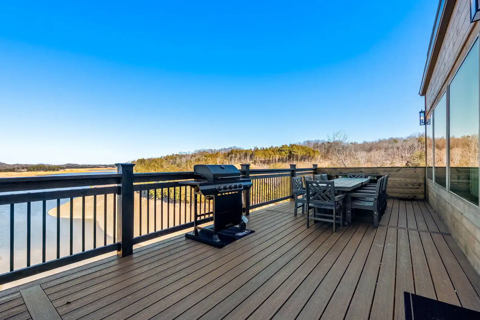 Spacious deck with a grill and dining area overlooking the lake