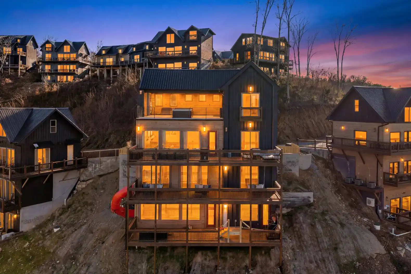 Stunning exterior view of a multi-level lakefront home with illuminated balconies