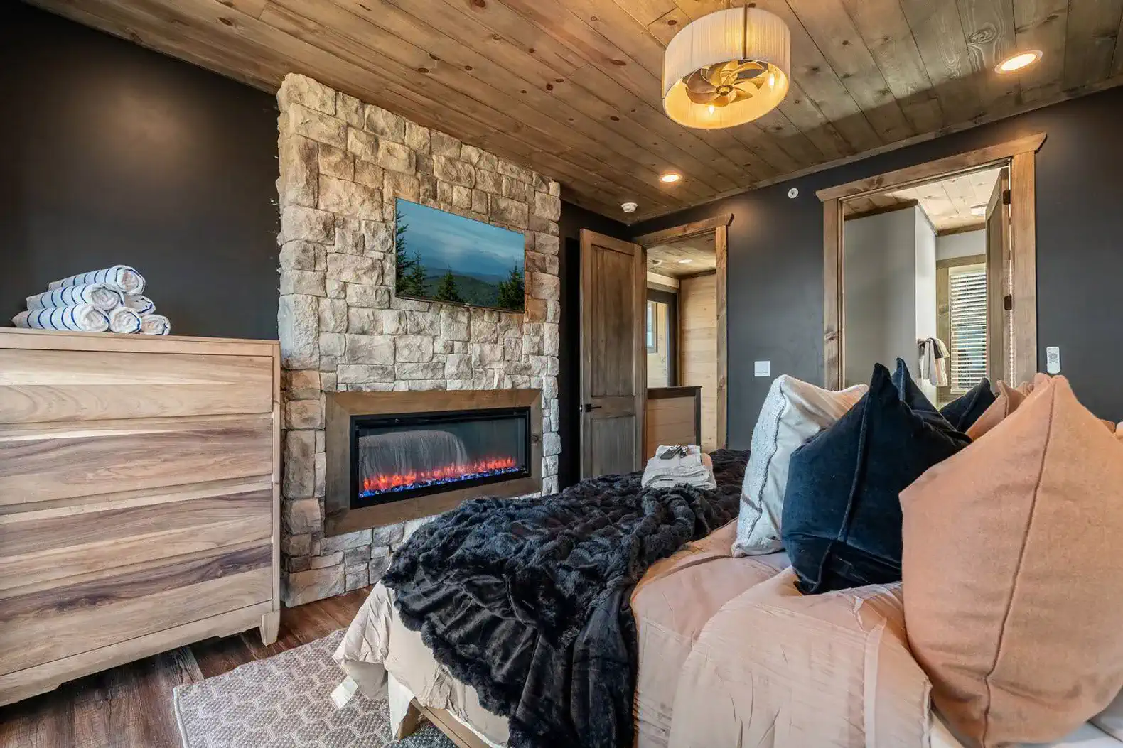 Cozy master bedroom with stone fireplace and plush bedding