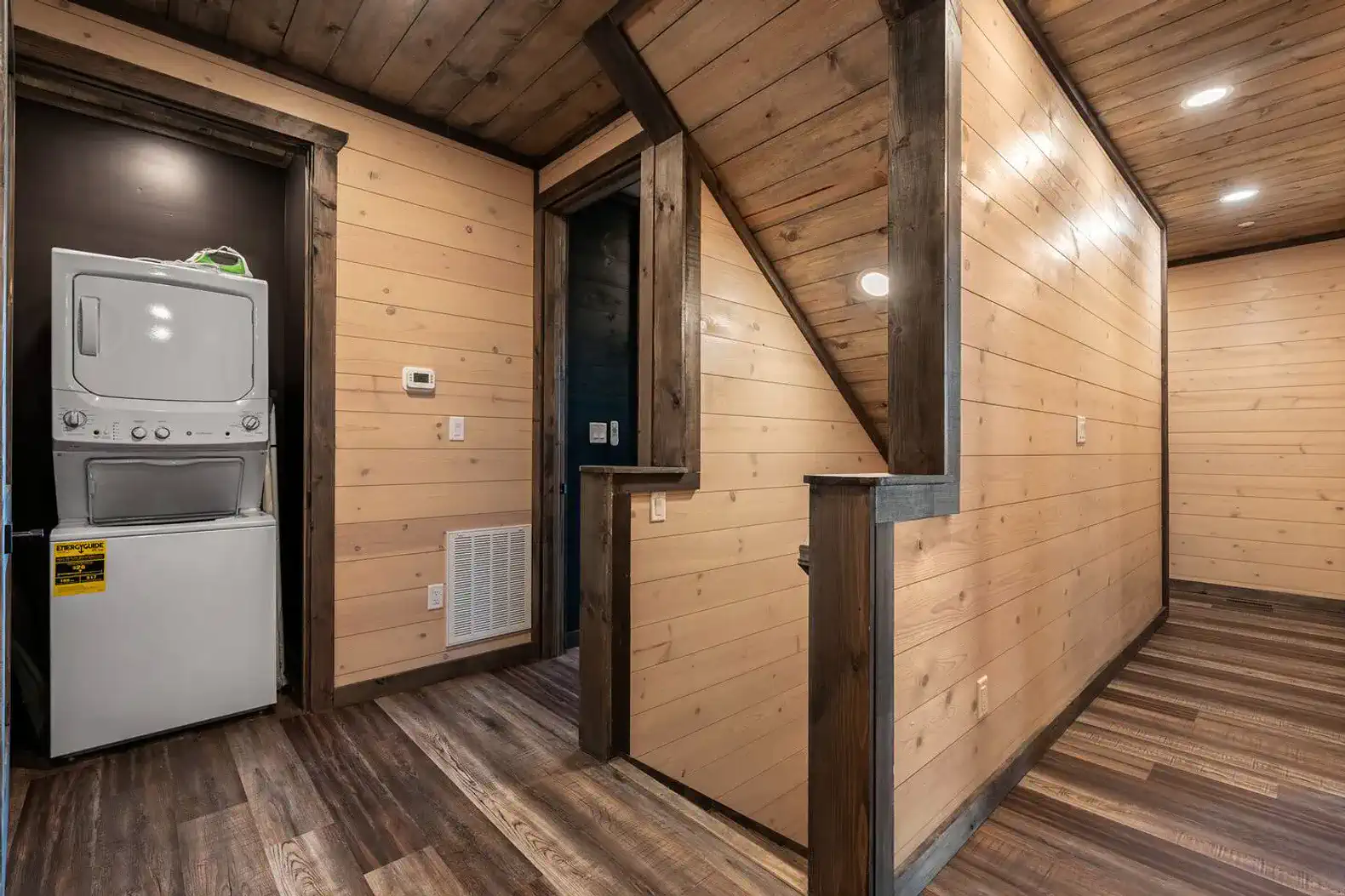 Laundry area with stacked washer and dryer in a wooden hallway