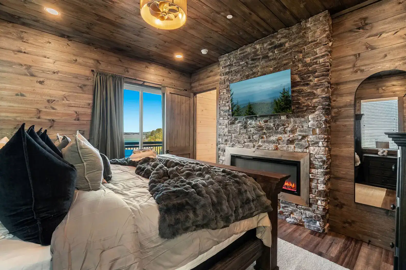 Cozy master bedroom with stone fireplace and lake view