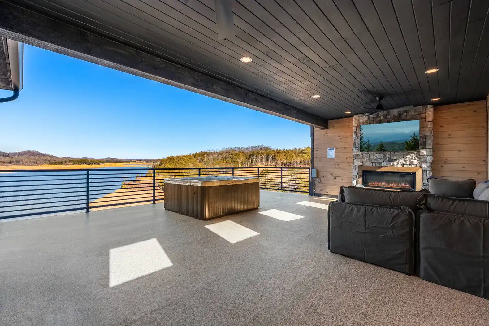 Spacious outdoor area with seating and fireplace overlooking the lake