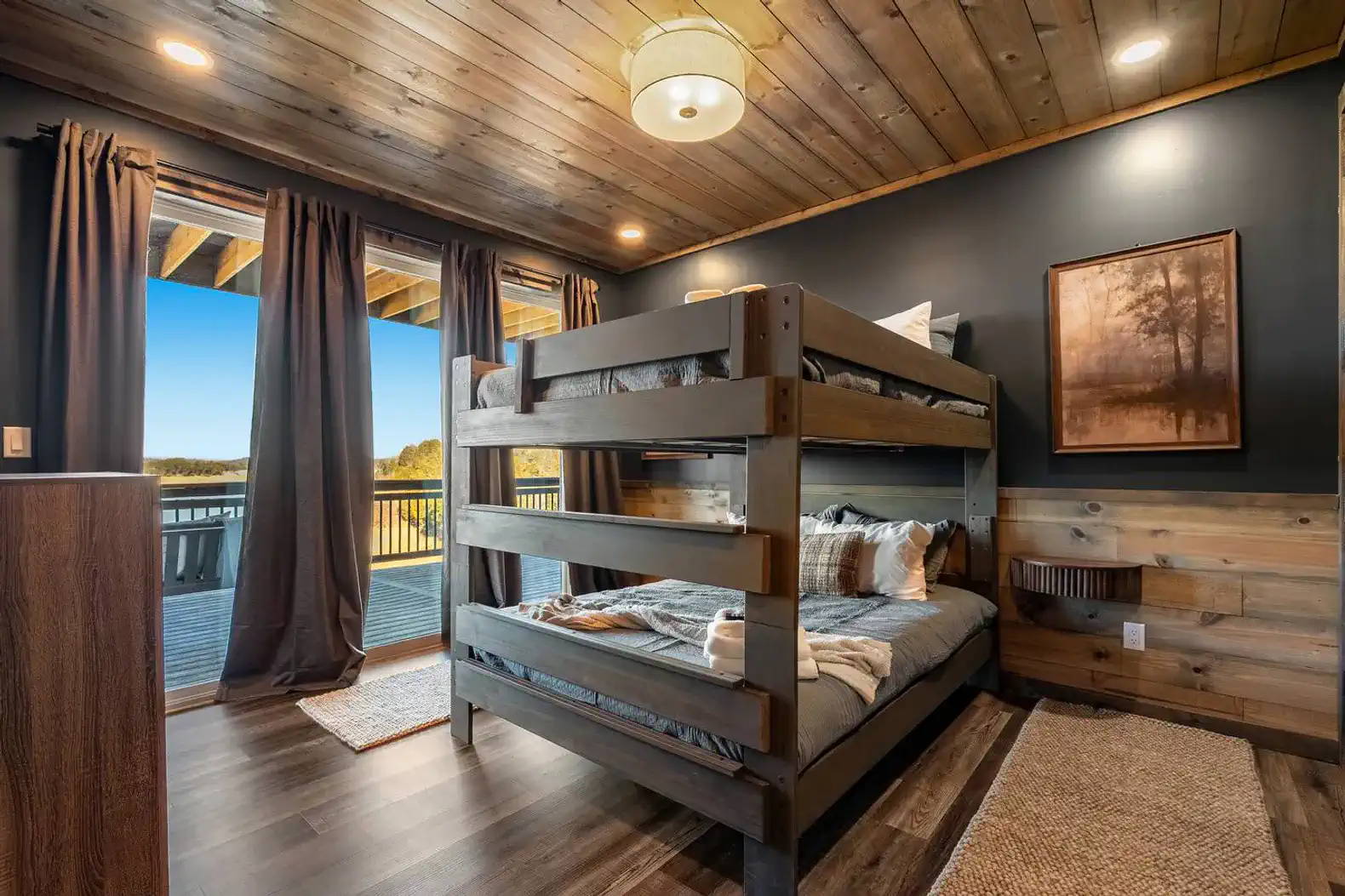 Cozy bunk room with wooden accents and large windows overlooking the lake