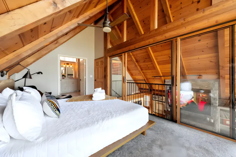 Primärsuite auf der Loft-Ebene mit King Nectar-Matratze, A-Frame-Holzdecke & Glasgeländer mit Blick auf das Wohnzimmer — der gemütlichste Schlafbereich in dieser Hütte am Lake Lanier in Gainesville, GA.